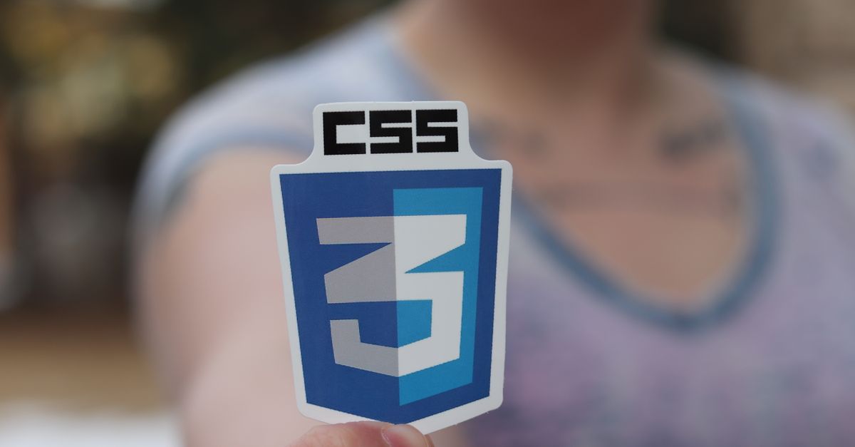 Close-up photograph of a CSS3 logo sticker held by a person with blurred background.